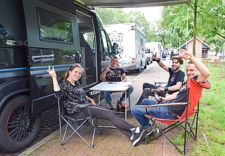 Aus Kyritz bei Wittstock kommen Vanessa (von links), Leon, Florian und Robin. Auf dem Parkplatz Forst Rantzau sitzen sie unter dem Vordach von Robins Camper auf Klappstühlen. Der Wagen bietet so viel Platz, dass alle vier darin übernachten können. (Foto: Frank)