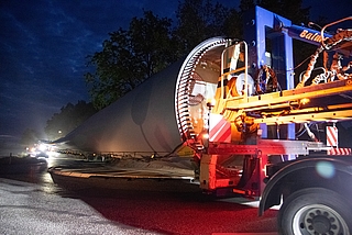 Ein Schwerlasttransporter fährt durch den Kreisverkehr zwischen Klein und Groß Nordende. Das bepflanzte Rondell war eigens für die Aktion zu etwa einem Viertel abgetragen worden, damit genügend Platz für die Rotorblätter und Fahrzeuge besteht. (Foto: Frank)